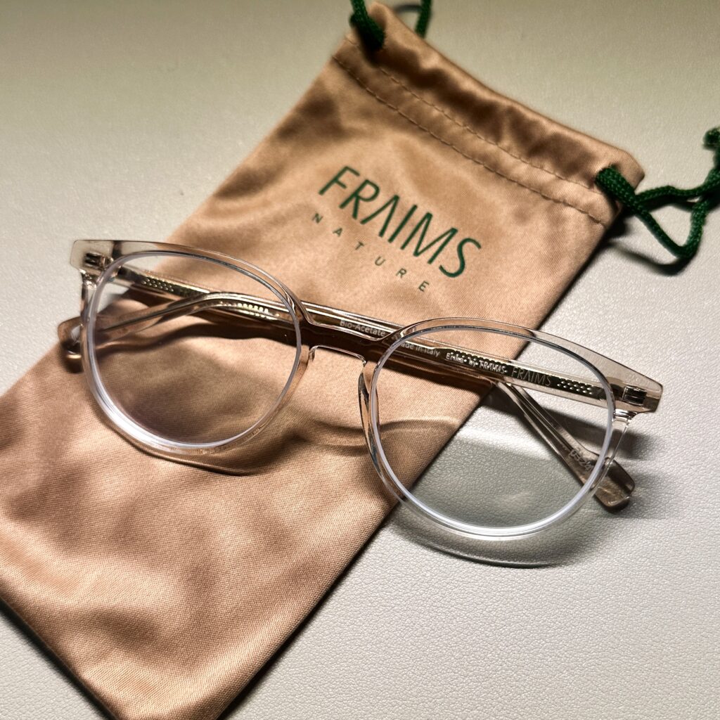 transparente FRAIMS-Brille liegt auf Brillenbeutel