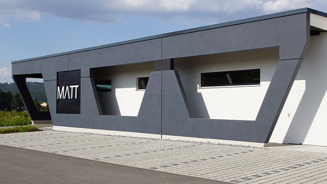 Die Außenfassade des neuen Standorts in Waldmünchen während der Bauphase. Verschiedene Werkzeuge und zwei Bauarbeiter in warmer Kleidung sind sichtbar.